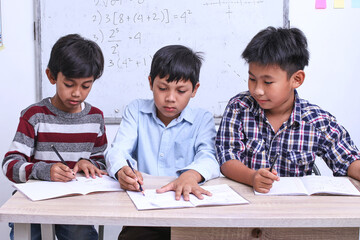 Group of student writing lesson on book at the classroom, practicing and finishing assignment together. 