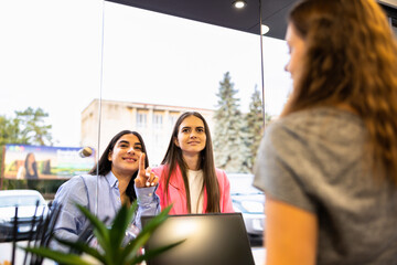 Friendly bartender serving espresso coffee to a middle-aged customer in the interior of a modern coffee shop.