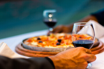 Gourmet dinner of two people enjoying pizza with red wine at a restaurant
