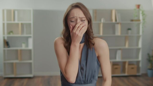 Portrait of a Sad Young Woman in a Dress is Crying in Front of a Mirror.A Depressed Woman is Sobbing and Wiping Tears, Going Through a Difficult Time. Party, Graduation, Date.Loneliness and Isolation.