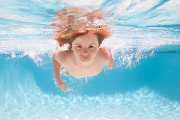 Fototapeta na wymiar Child in pool in summer day. Young boy swim and dive underwater. Under water portrait in swim pool. Child boy diving into a swimming pool.