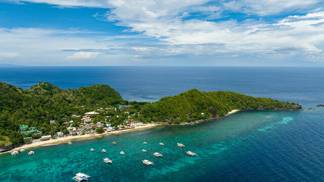Tropical island with a beach. Apo Island. Popular dive site and snorkeling destination with tourists. Negros, Philippines.