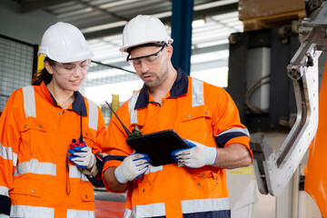 Engineer man and woman talking and discussion about robot arms technology intelligence and innovation while looking digital tablet at factory, people meeting and check machine robot, industry concept.
