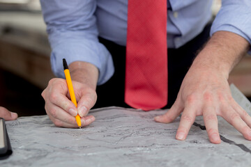 Closeup hands of team architect or engineer man meeting for planning of development real estate at construction site, contractor and partner talk and look blueprint, two people, industrial concept.