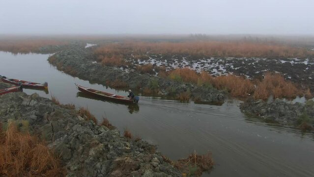 Man drives canoe on river at Mesopotamian Marshes in Iraq, aerial