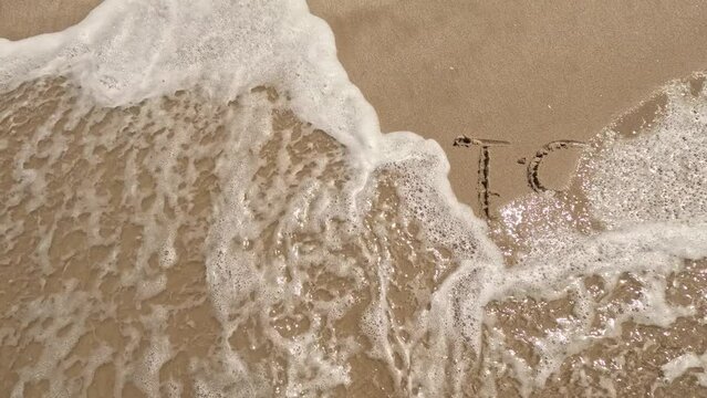 "crisis" word is written on the beach sand and erased with a wave, a concept video of the economic world crisis.