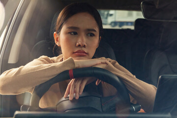 Asian woman with her hands on the steering wheel feeling exhausted, stressed with work, thinking...