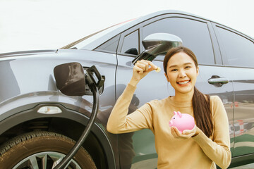 Portrait young asian woman driving an EV electric car In the process of charging smile good mood...