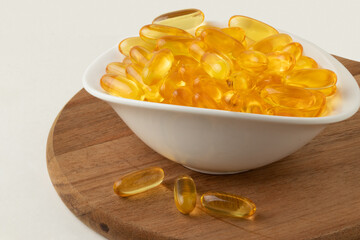 Fish oil capsules in a bowl. Omega 3 supplements.