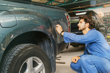Male worker inspecting pickup truck, paint mechanic examining scratched car surface body damage near wheel arches using white chalk to paint circles to repair in auto workshop factory with insurance. © ฺฺฺBoonterm
