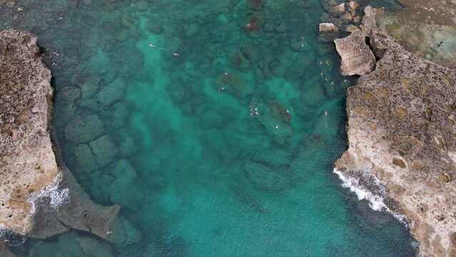 Aerial overview of swimmers in a secluded beach cove tracking forward in Hawaii 