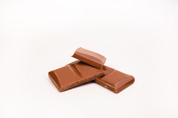 Chocolate on a white background. Broken milk chocolate cubes.