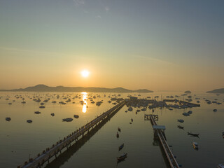 Obraz premium aerial view beautiful sunrise cloud above Chalong pier..Sunrise with sweet yellow color light rays and other atmospheric effects..colorful reflection of sunrise in the sea background.