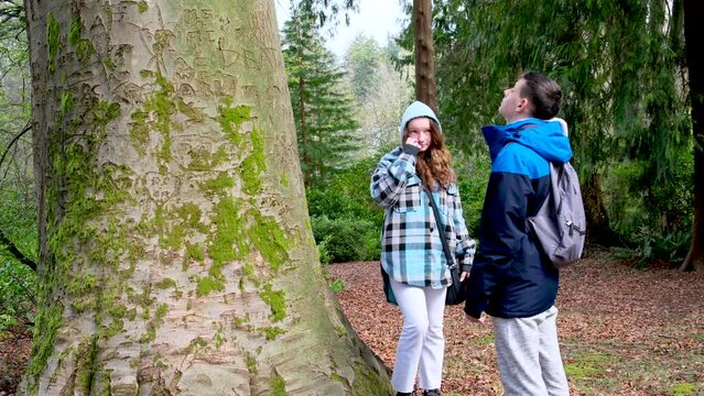 stanley park teenagers walking taking pictures fooling around looking at trees chatting autumn spring cool weather tourists backpacks phones fun first date walk hold hands sportswear boy and girl