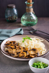 Udon noodles and fried mushrooms on a plate for homemade dinner vertical view