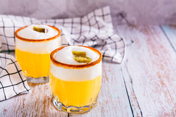 Homemade spicy cocktail with margarita, egg white foam, tagine and jalapeno peppers in glasses