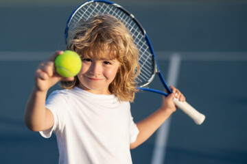Tennis kid. Child with tennis racket and tennis ball playing on tennis court.