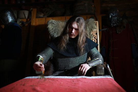 A mighty hero with long hair in chain mail armor in an ancient hall. Medieval warrior in the knight's chambers.