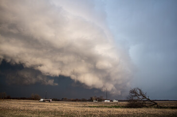 Fototapeta na wymiar A huge storm with a shelf cloud approaches rapidly over a farmland landscape.