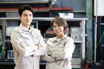 Male and female workers in a factory, looking at the camera