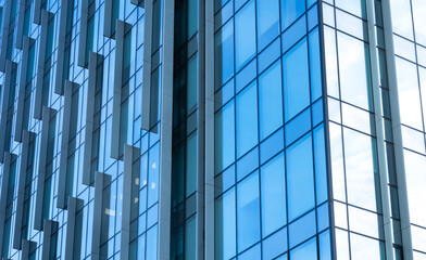 The blue sky is reflected in the windows of a modern office building. Architecture and exterior of contemporary houses