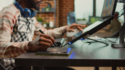 Male photographer working on image editing with retouching software, using tablet and stylus to create media production at creative agency. Artist creating picture edit with color grading.