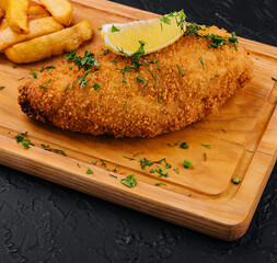 Breaded schnitzel with french fries on a cutting board