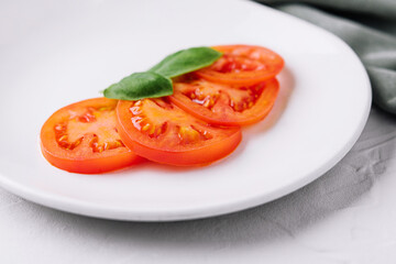 Sliced red tomatoes and basil leaves