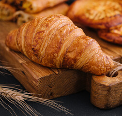 Fresh croissant and buns on wooden board