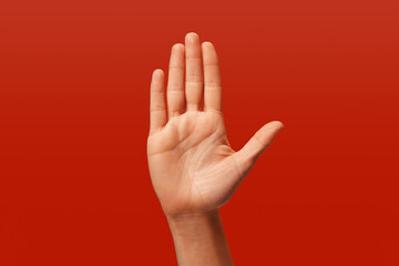 white woman making stop sign with her hand, on red background