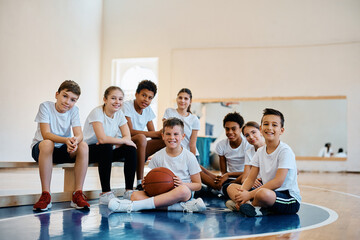 Multiracial group of happy kids having physical activity class at school gym and looking at camera.