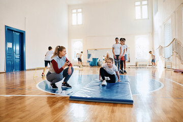 Fototapeta na wymiar Elementary students having physical activity class with sports teacher at school gym.