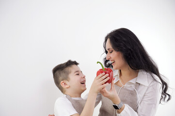 Happy woman chopping red bell pepper while standing with children in kitchen. High quality photo
