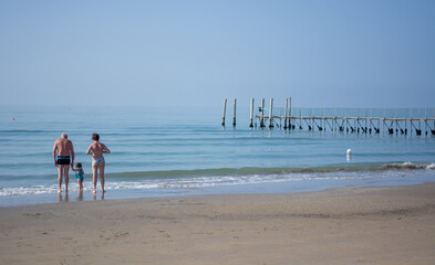 grandparents take the child to touch the water of the sea