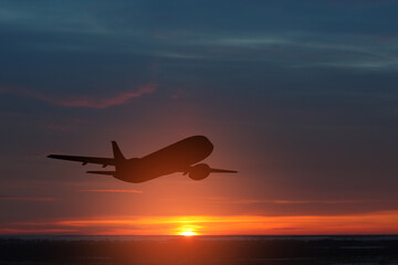 Fototapeta na wymiar Airplane taking off at the sunset sky.