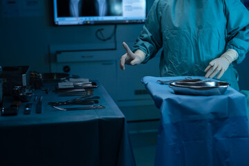 Doctor is standing on table choosing equipment be used for surgery come put it on tool tray near hand for ease use, prepare patients who sleep in room before surgery, clean safe medical equipment.