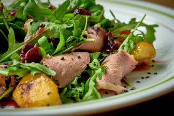 Salad with roast beef, arugula, caramelized onions in a plate on a wooden background