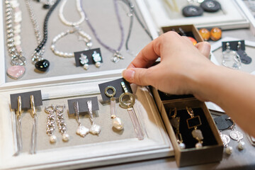 woman's hand delicately selects a handmade earring from a display, showcasing an array of artisanal...