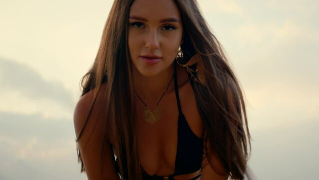 beautiful girl with long straight hair dancing on the beach, watching the sunset