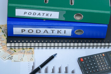 Dokumenty firmowe w segregatorach obok gotówki, długopisu i kalkulatora
