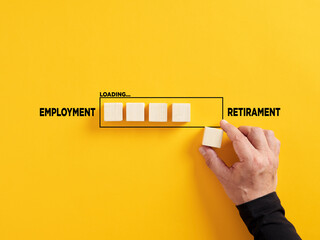 Transition of career timeline from employment to retirement. Retirement loading. Hand places a wooden cube to the loading bar with the words employment and retirement.