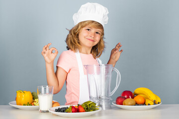 Cooking children. Chef kid boy making fresh vegetables for healthy eat. Portrait of little child in form of cook isolated on grey background. Kid chef. Fruits and vegetables for kids.
