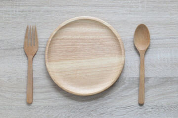 Wooden bowl with spoon and fork on wooden background