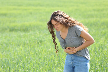 Woman suffering belly ache in a field