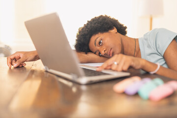 Young black woman exhausted from studying on her laptop