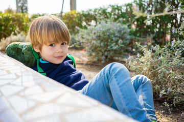 Child on spring nature background. Sweet, happy child boy playing upside down on a grass in a park at a spring. Laughing, enjoying fresh. Funny kids.