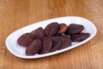 Dried apricots. Organic sun-dried apricots on wood background. Naturally Dried apricots color orange in a ceramic bowl