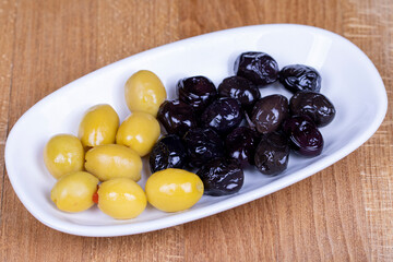 Green stuffed olives and black olives. Naturally olive in a ceramic bowl. Close up
