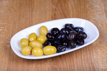 Green stuffed olives and black olives. Naturally olive in a ceramic bowl
