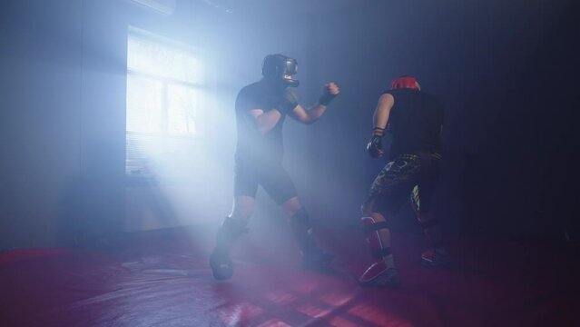 Sparring of two boxers on a red mat. Athletes improve their skills. Training with the use of all ammunition. High quality 4k footage